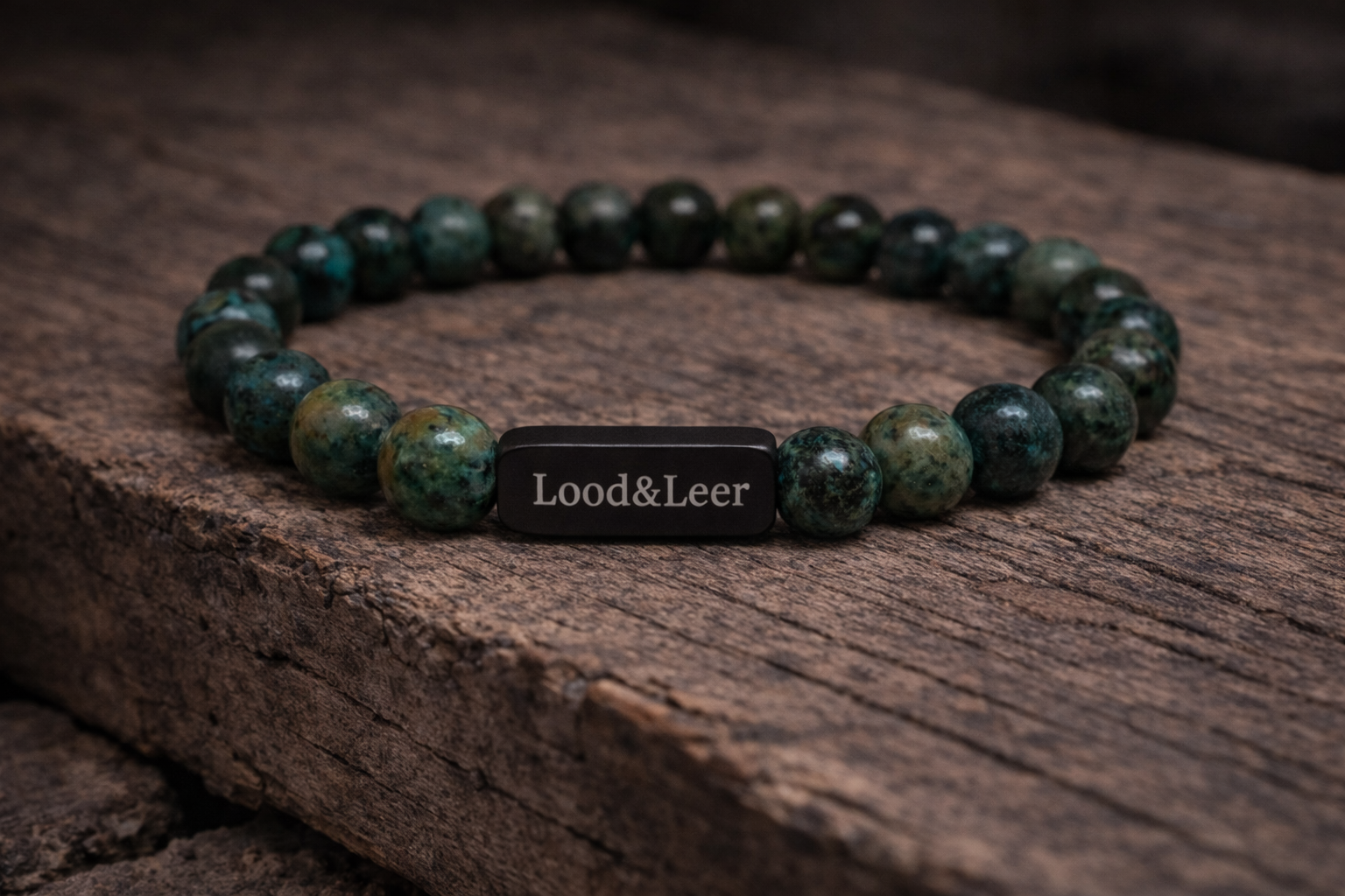 Volledig zicht op een herenarmband van Afrikaanse turkoois natuursteen met zwarte Lood & Leer tag, gefotografeerd op hout.