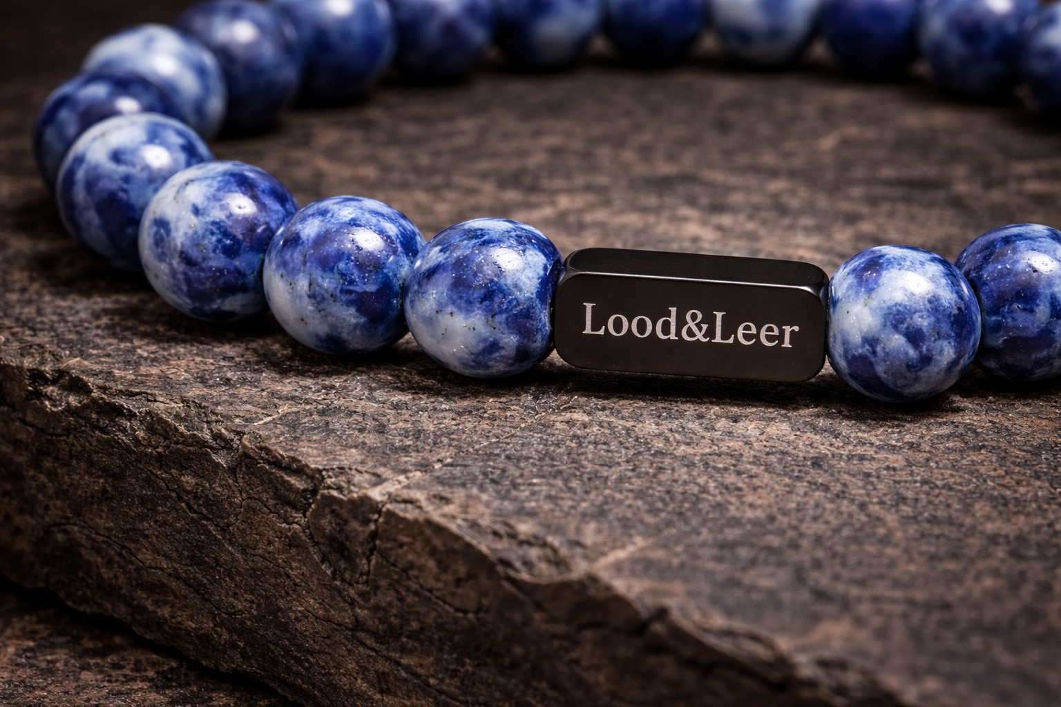 Close-up van sodaliet natuurstenen armband met zwarte Lood & Leer tag op een robuuste houten ondergrond